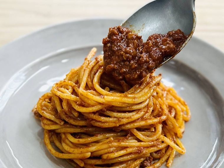 パスタにボロネーゼソースをかけている様子