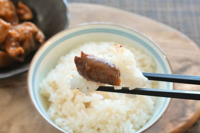 白いごはんとコチュジャン味のホルモンを黒い箸で食べる様子