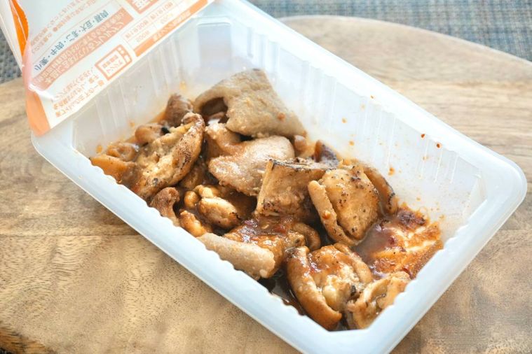 木のカッティングボードにのった白いパック入りのホルモン