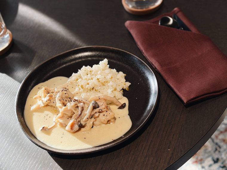 黒い器に盛られた地鶏フリカッセとバターライスと、赤いカトラリーカバー