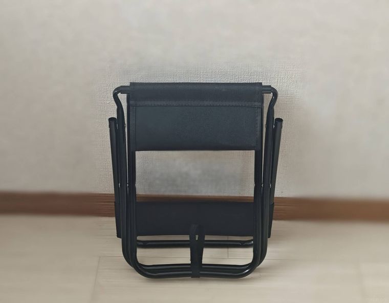 背もたれ付き折りたたみ椅子を壁にかけている様子