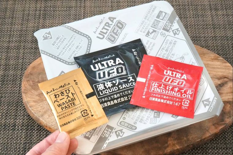 木のカッティングボードにのったカップ焼きそばと調味ソース