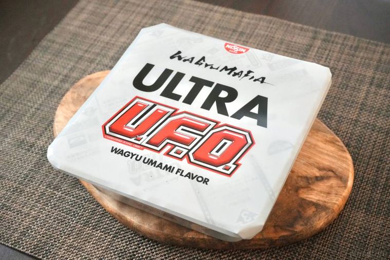 木のカッティングボードにのった白いパッケージのカップ焼きそば