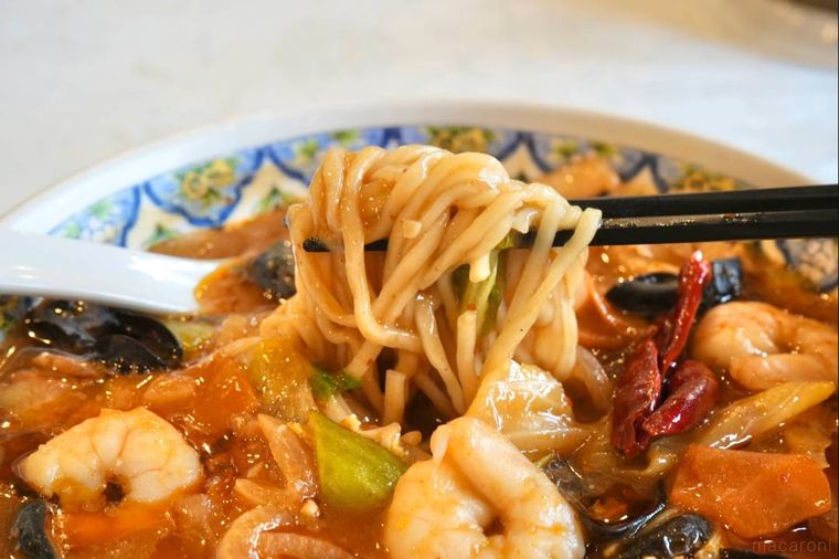 麻辣麺の麺を黒い箸で持ち上げる様子