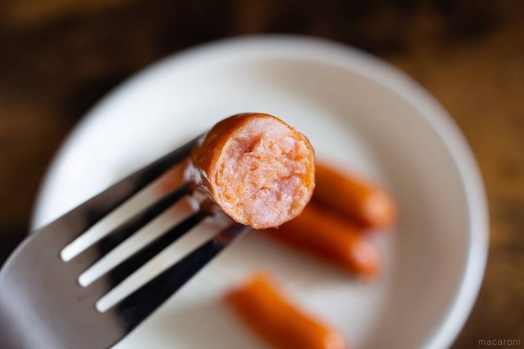 半分に割った丸大食品燻製屋 熟成あらびきウインナー 旨辛チョリソーをフォークで箸上げしている様子