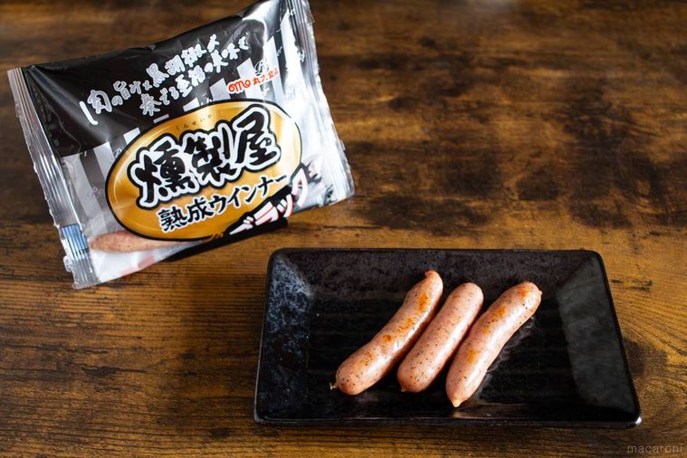 燻製屋 熟成あらびきウインナー 燻製ブラックペッパーのパッケージと調理したウインナーを盛り付けたお皿が並んでいる