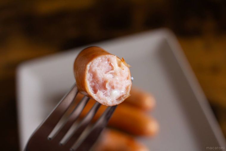 丸大食品燻製屋 熟成あらびきウインナー とろける濃厚チーズをフォークで箸上げしている様子