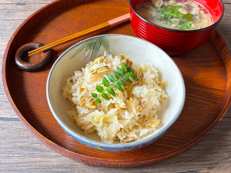 お盆にのせられた茶碗に盛られたあさりの炊き込みご飯、みそ汁