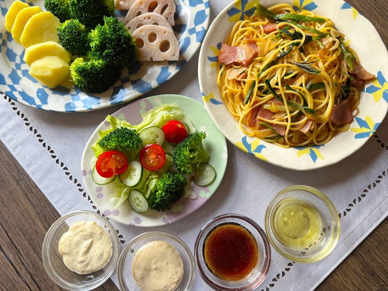 ドレッシングとパスタ、温野菜、サラダを並べたテーブル