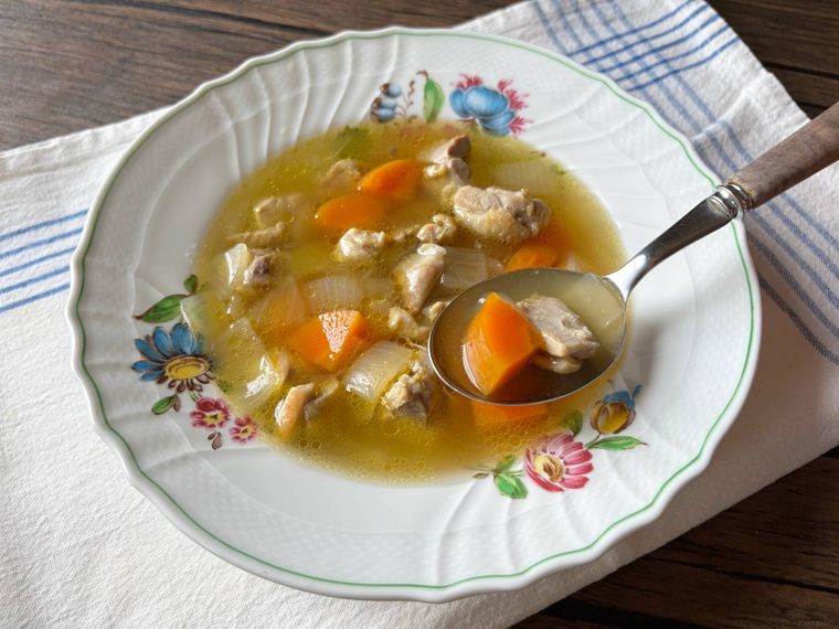 スープ皿に入ったチキンスープをスプーンですくう様子