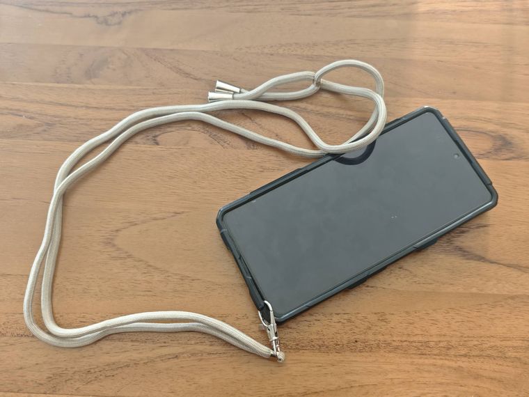 スマホケース用肩かけストラップを付けたスマホが机の上に置いてある