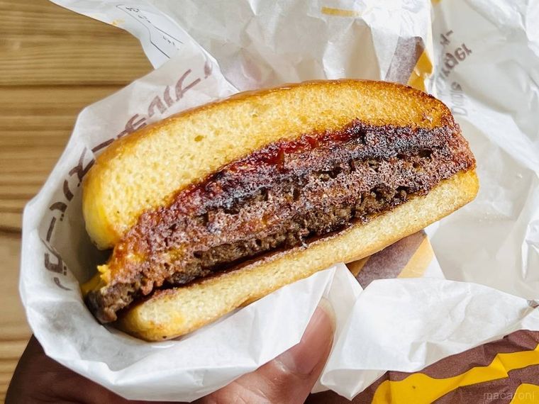 バターで焼いたダブルチーズバーガーを手で持っている様子