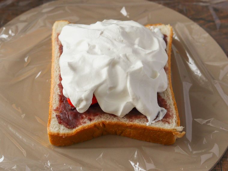 食パンにホイップクリームをのせている。