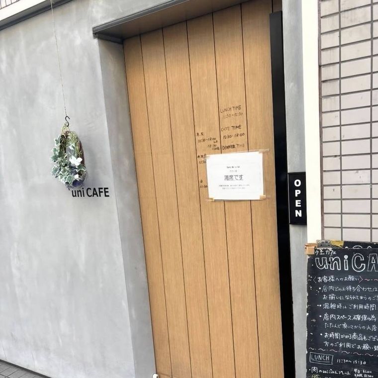 コンクリート調の壁に木の扉がおしゃれな外観