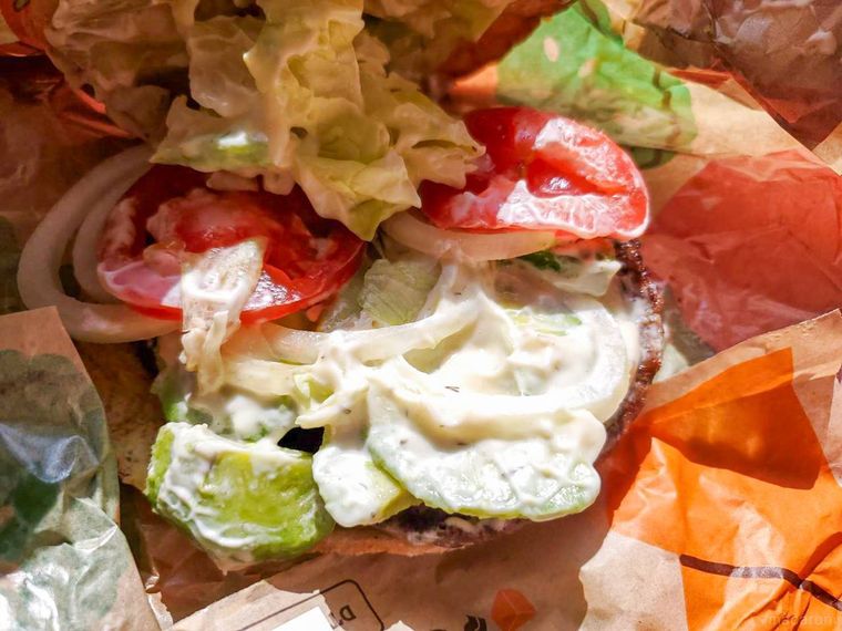 バンズを持ち上げて、バーガーキングクリーミーマヨ アボカドワッパーの具材を見ている様子