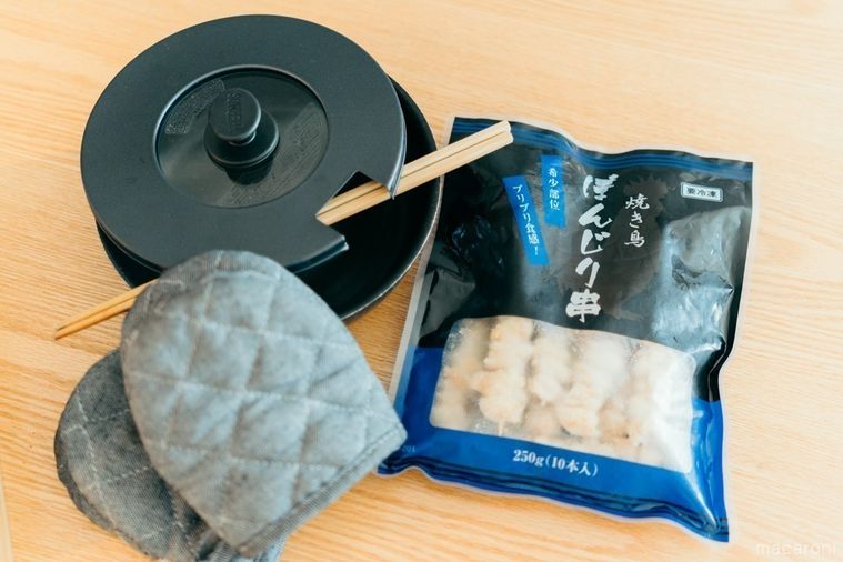 テーブルの上に置かれたぼんじり焼き鳥串とフライパン、菜箸と鍋つかみ