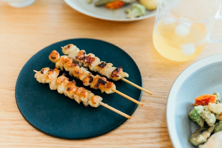 黒いお皿に置かれたフライパン調理のぼんじり焼き鳥串3本