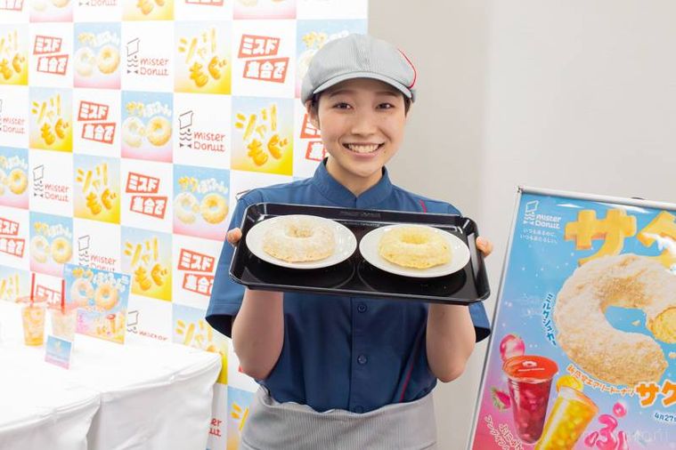 トレーにのせたサクぽふんを持って笑顔を見せるミスタードーナツのスタッフ