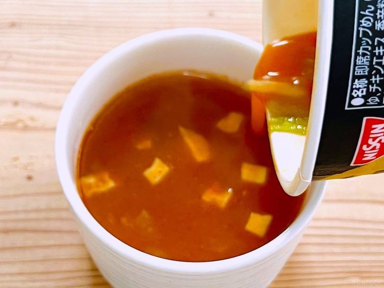 卵を入れた蒙古タンメン中本 辛旨味噌の残り汁を耐熱容器にそそいでいる様子