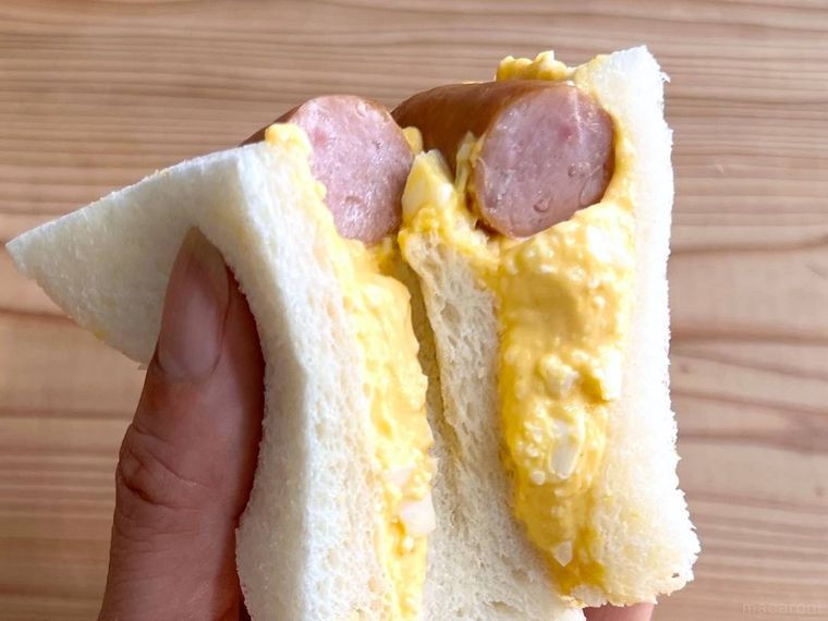 ンビニのたまごサンドに、丸大食品の燻製屋熟成あらびきポークウインナーを挟んだ様子