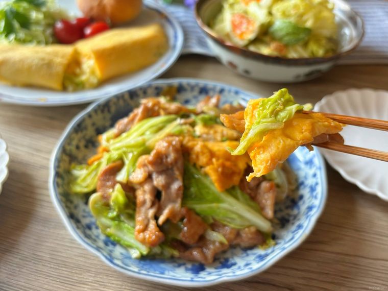 和皿に盛り付けた春キャベツと卵、豚こま肉の中華炒めを箸あげする様子
