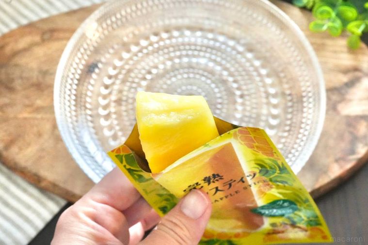 木のカッティングボードにのったガラスの器と冷凍完熟パイナップルスティックを手に持つ様子