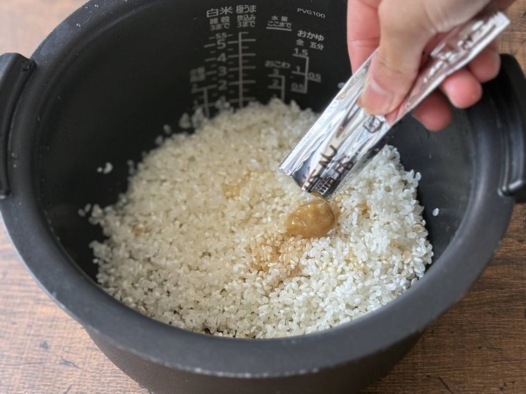 炊飯ジャーに調味料を加えて混ぜている。