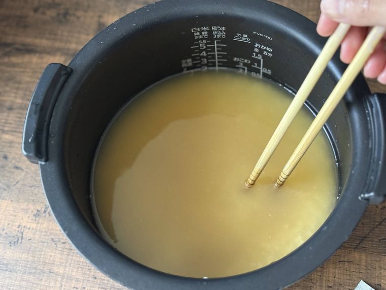 炊飯ジャーに調味料を加えて混ぜている。