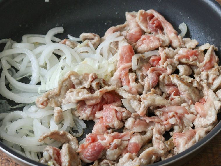 豚肉と玉ねぎをフライパンで炒めている
