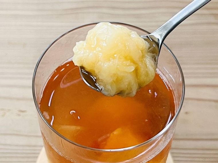 アイスティーに入ったアヲハタ まるごと果実 白桃の果肉をスプーンですくった様子