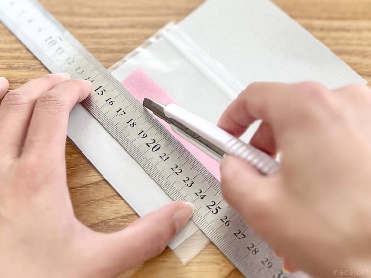 マスキングテープを貼ったチャック付き袋に切り込みを入れている様子