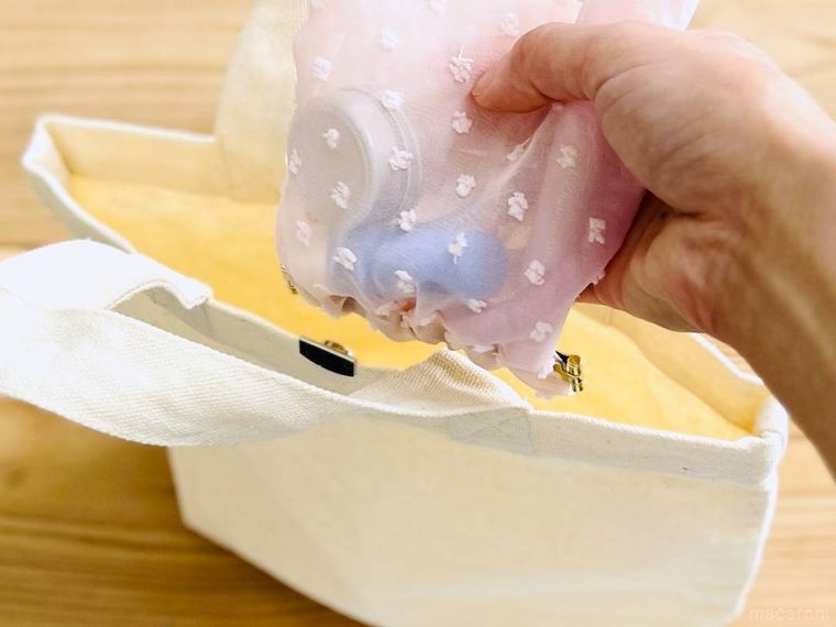 ピンク色のバネ口ポーチを白いバッグに入れようとしている様子