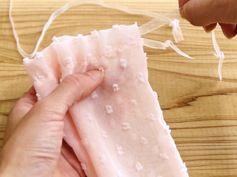 ピンク色の巾着のヒモを抜いている様子