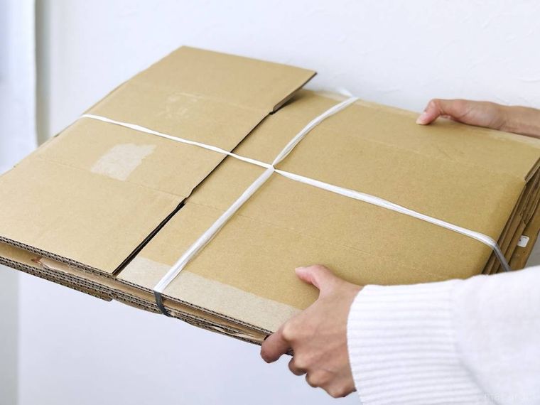 束ねたダンボールを両手で持っている様子