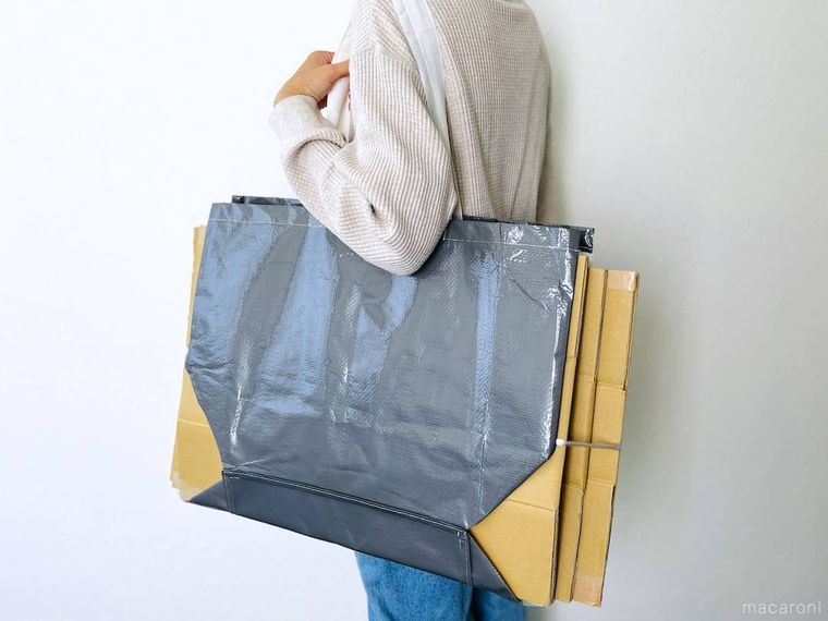 グレーのppバッグでダンボールを挟み、肩に掛けた様子