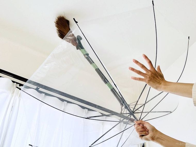 ほうきを貼りつけた傘で天井を掃除している様子