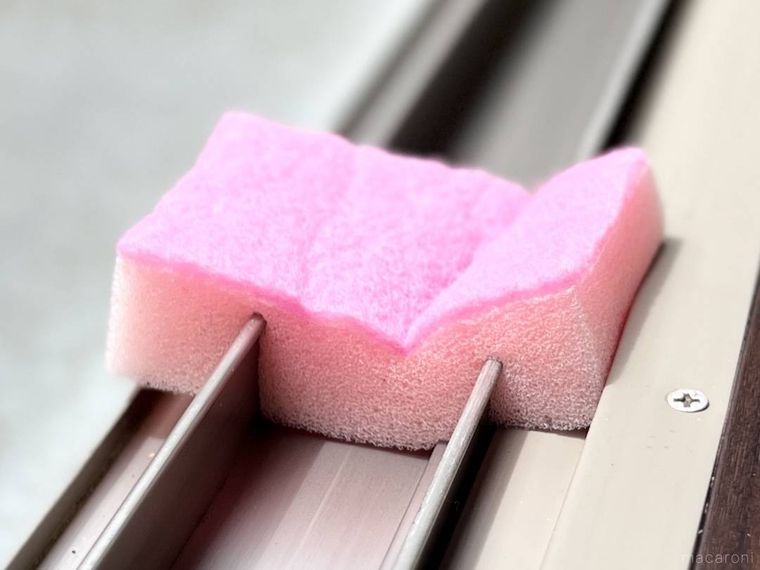 切り込みを入れた食器用スポンジで窓のサッシを掃除している様子