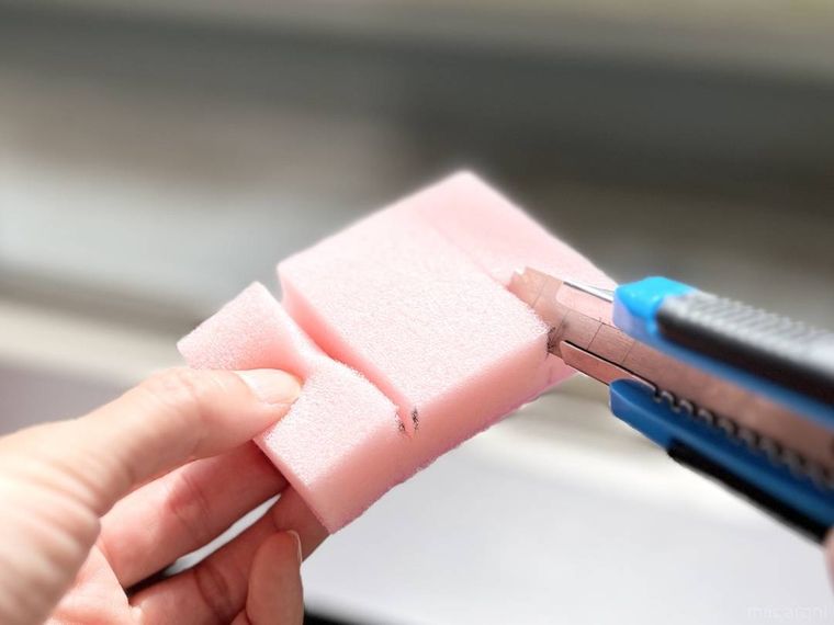 ピンク色の食器用スポンジにカッターで切り込みを入れている様子