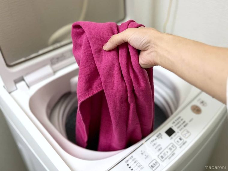 洗濯機にピンク色のバスタオルを入れようとしている様子