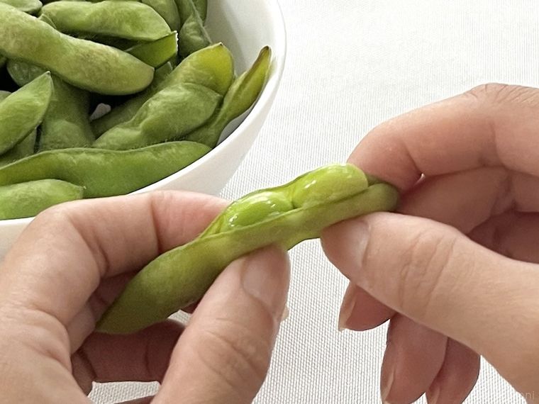 ゆでた枝豆をさやから出そうとしている様子