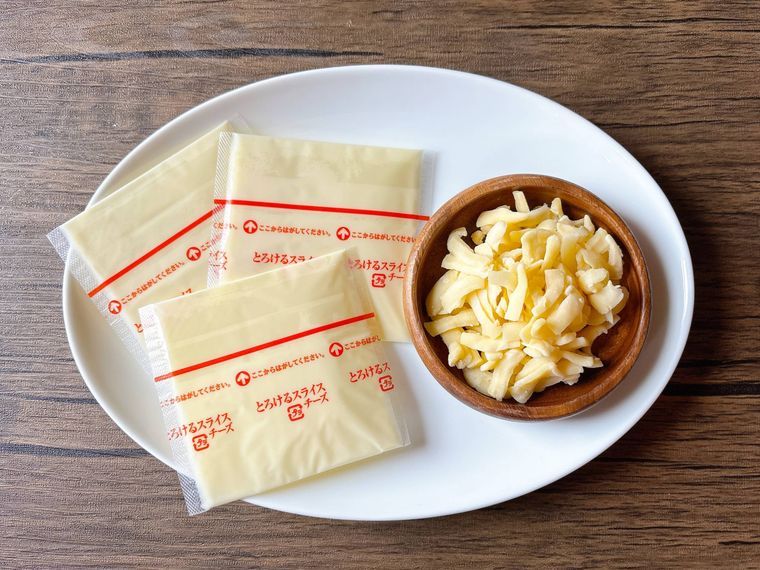 白色の皿に盛られたピザ用チーズ、とろけるスライスチーズ
