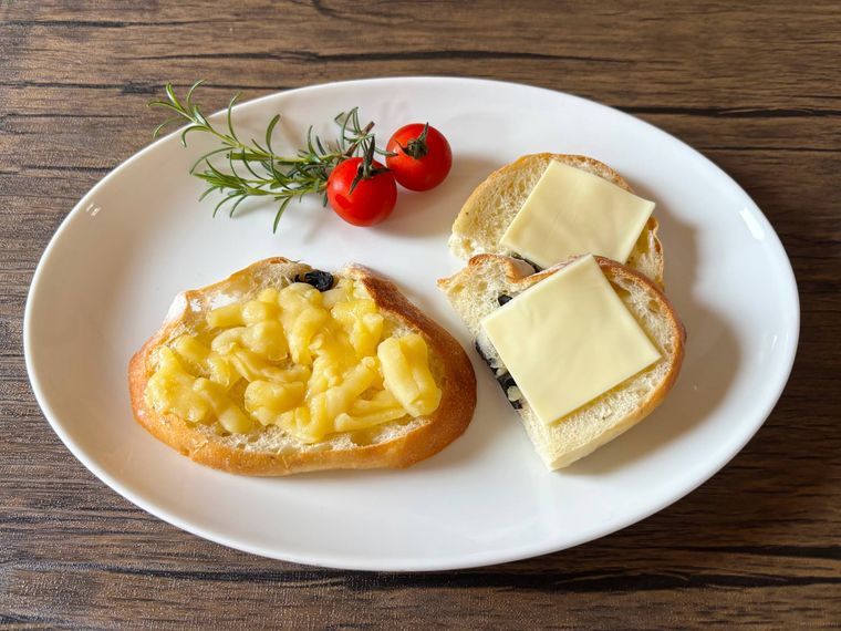 白色の皿にとろけるチーズをパンにのせたもの