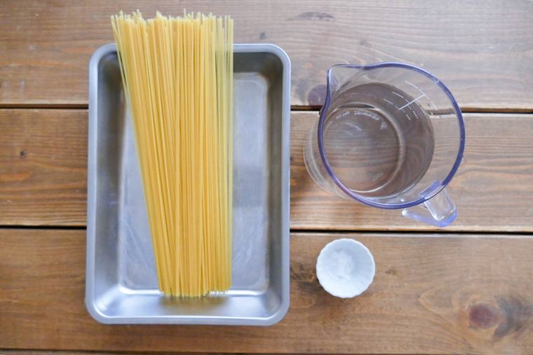 スパゲッティ、水、塩がある木製テーブル