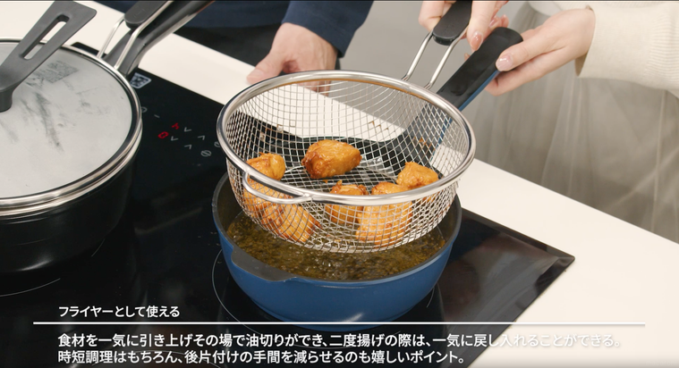 唐揚げの入ったストレーナーを引き上げている