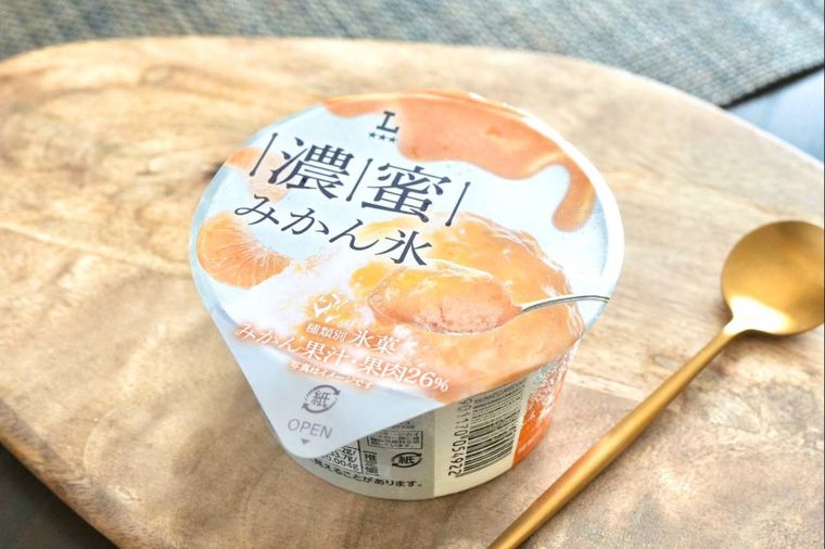 木のカッティングボードにのったコンビニのみかん果肉入りのかき氷