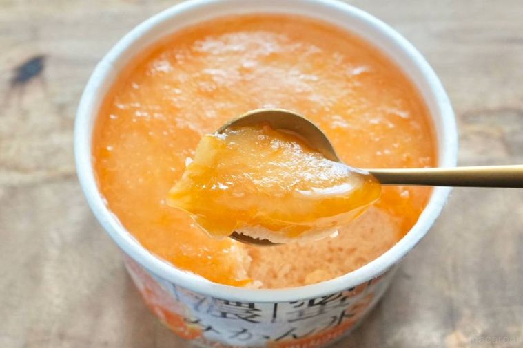 木のカッティングボードにのったみかん果肉入りのかき氷を金のスプーンですくう様子