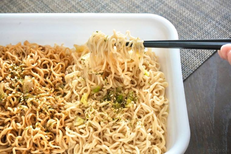 白い容器から塩焼きそばを黒い箸で持ち上げる様子
