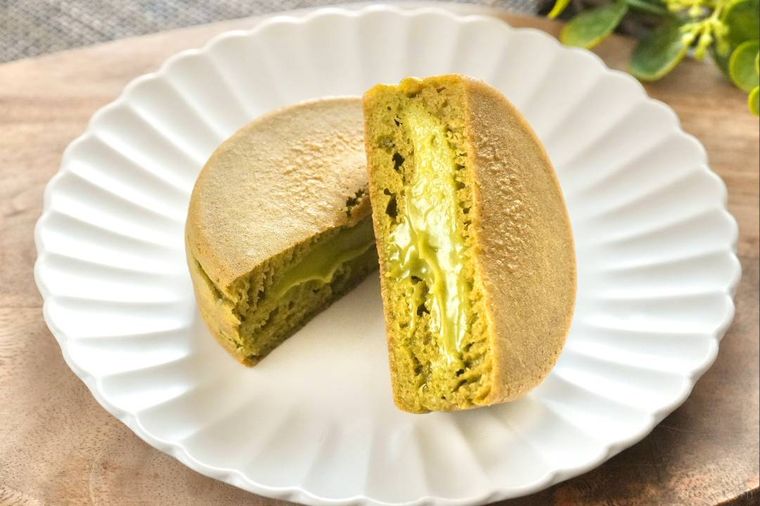 木のカッティングボードと白い皿にのった抹茶クリームの今川焼きの断面