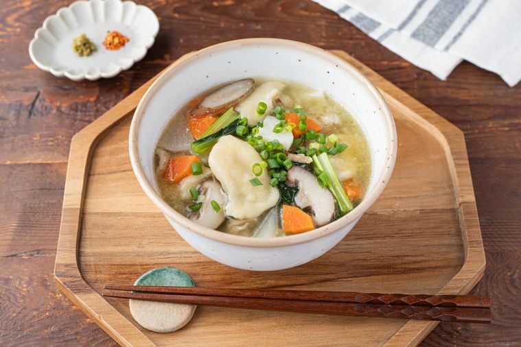白い器に盛り付けられただご汁と柚子胡椒と七味唐辛子をのせた小皿