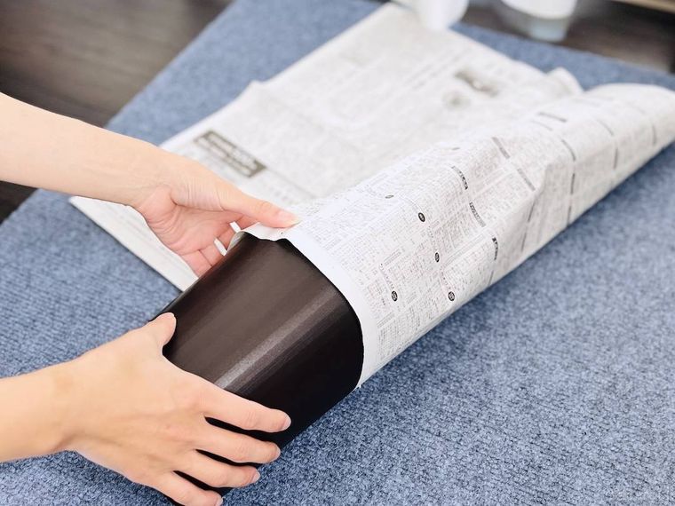 ゴミ箱の上部に新聞紙を巻き付けている様子